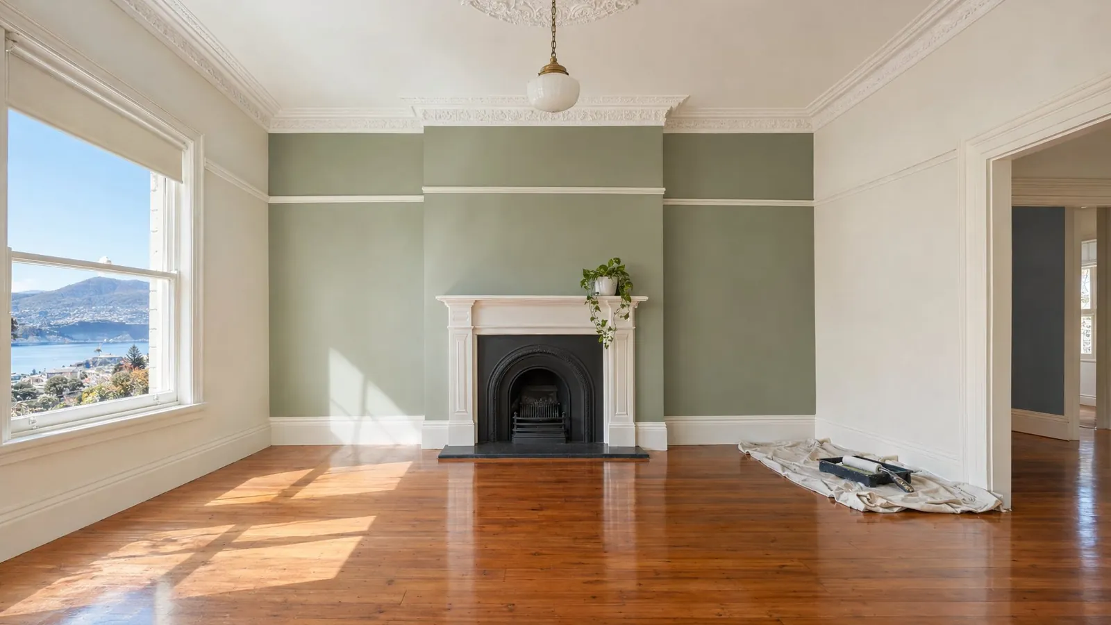 A freshly painted living room with a sage feature wall and ornate cornice.